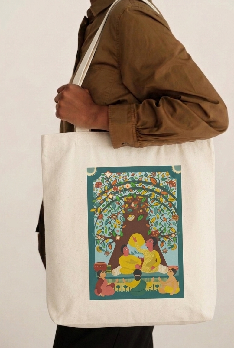 Person holding a tote bag with a colorful design of a bear and people sitting under a tree.